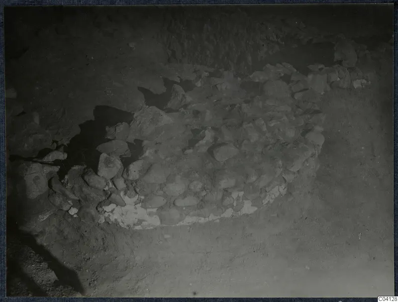 Excavation at Soli showing a curved stone construction of rounded stones set in soil