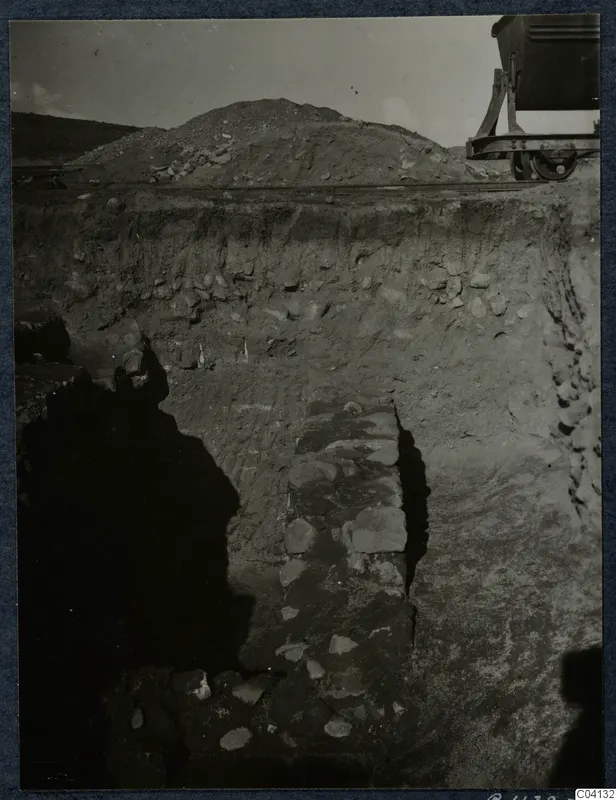 Excavation trench at Soli with a line of stones in the cut and a rail-mounted cart at upper right
