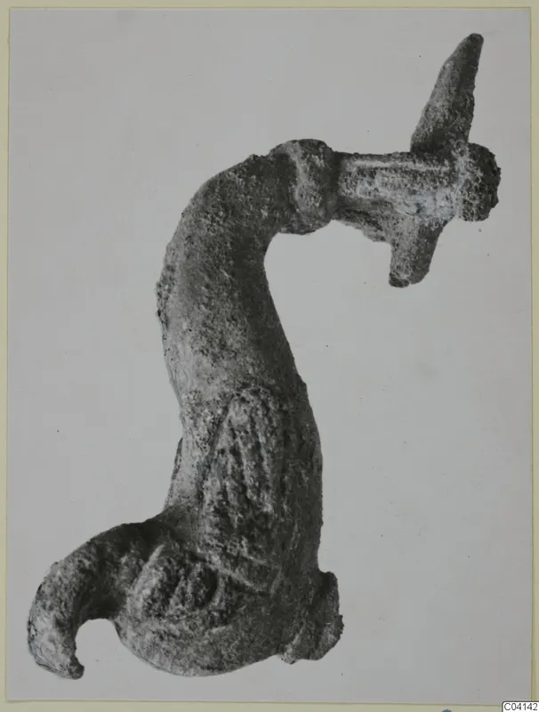 Corroded bronze object with a curved shaft, a flat crosspiece with a pointed spike, and a hooked lower end