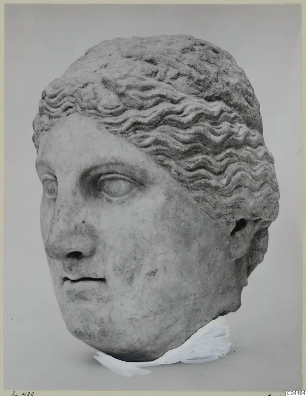 Marble head of a woman with wavy hair swept back, shown against a grey backdrop.