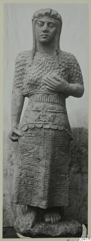 Stone statue of a standing figure from Soli, shown from the front against a pale backdrop