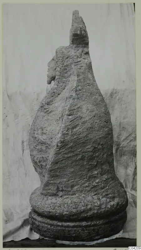 Weathered stone sculpture from Soli, with a head at the top and a face in profile on the left side.