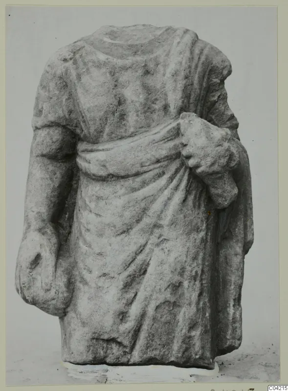 Headless stone statue torso from Soli, wearing a draped garment, one arm bent up holding cloth at the chest.