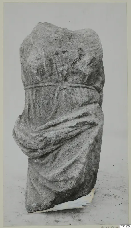 Stone sculpture fragment from Soli showing a draped figure with a band at the waist and an arm wrapped in cloth.