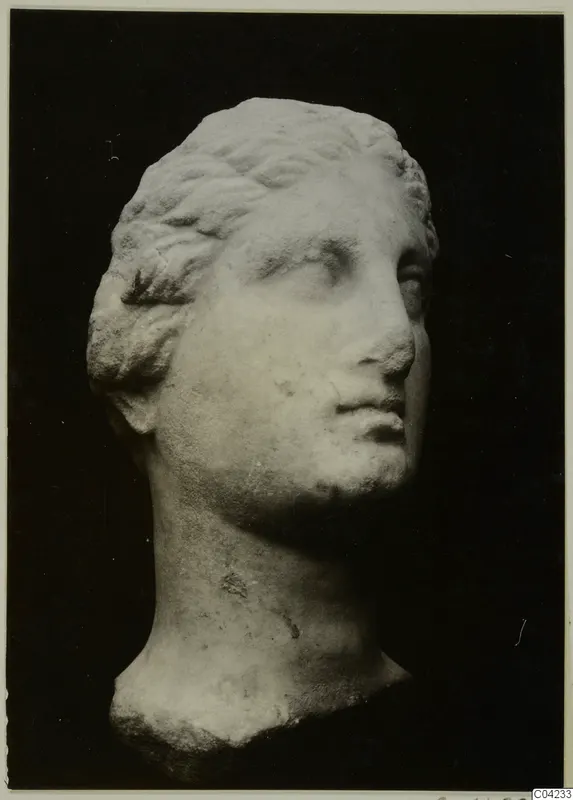 Marble head of a figure with wavy hair combed back, shown in three-quarter view against a black background.