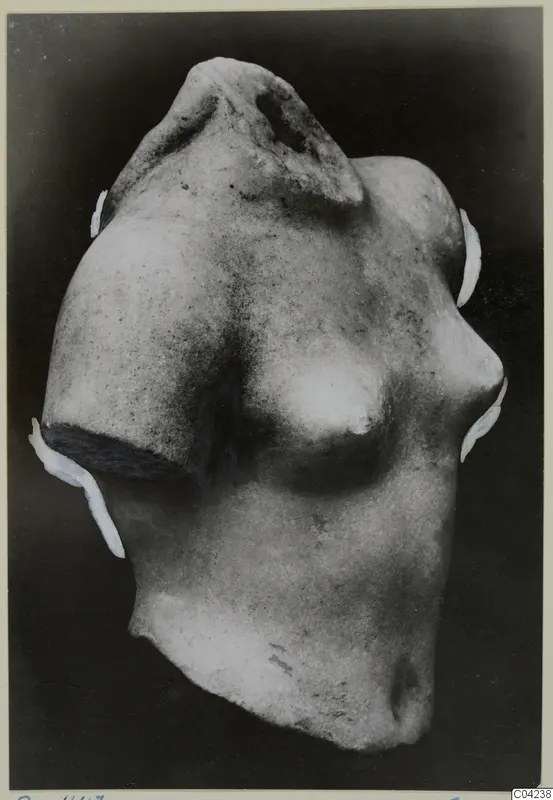 Fragment of a marble sculpture: a torso with a broken neck and shoulder, shown against a dark background