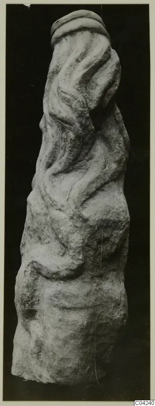 Carved stone sculpture fragment with wavy ridges and a rounded band at the top.
