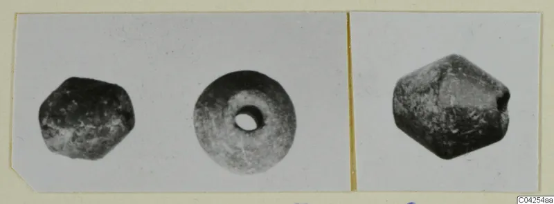 Three small dark beads from Milia, shown in separate views on a mounted print.