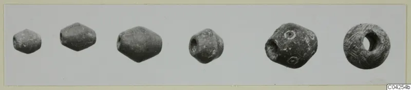 A row of small beads, biconical and rounded, shown side by side on a light photo card