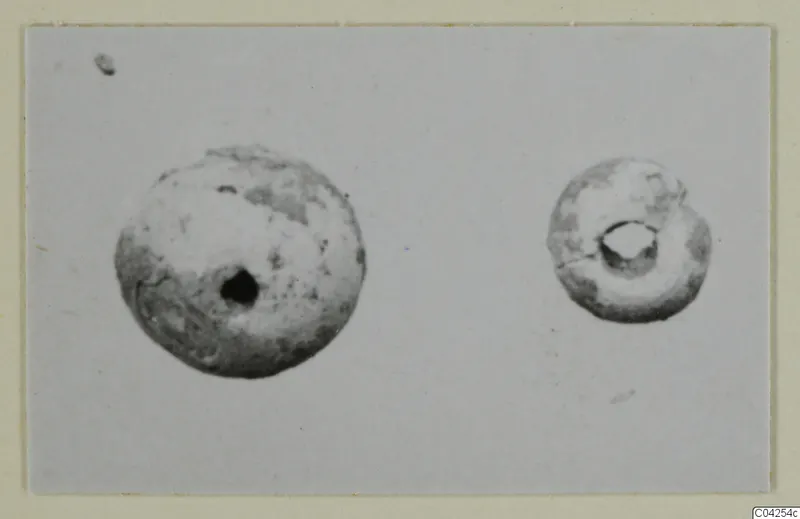 Two small perforated beads, one larger than the other, photographed on a plain grey background.