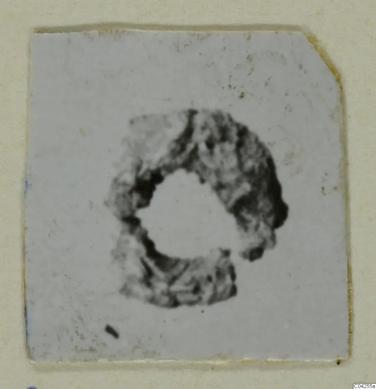 Lead object, a rough ring shape, shown as a small print on a card