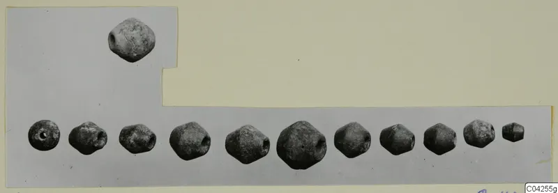 Twelve grey perforated beads, one set above and eleven in a row, on a grey card mount