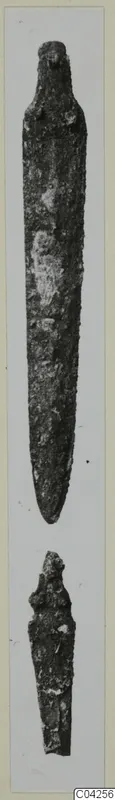 Two corroded bronze tools from Milia: a long tapering blade and a shorter broken fragment below it.