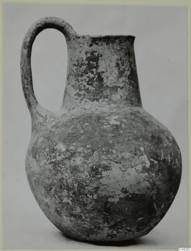 Pottery Black Slip Ware jug with a single loop handle and a rounded body, shown against a plain background