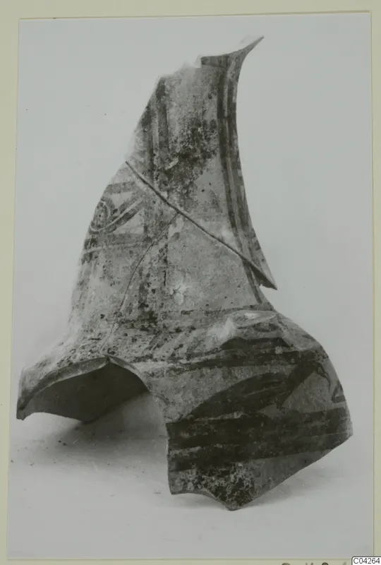 Large pottery sherd with dark painted bands and a curved motif, photographed on a pale background