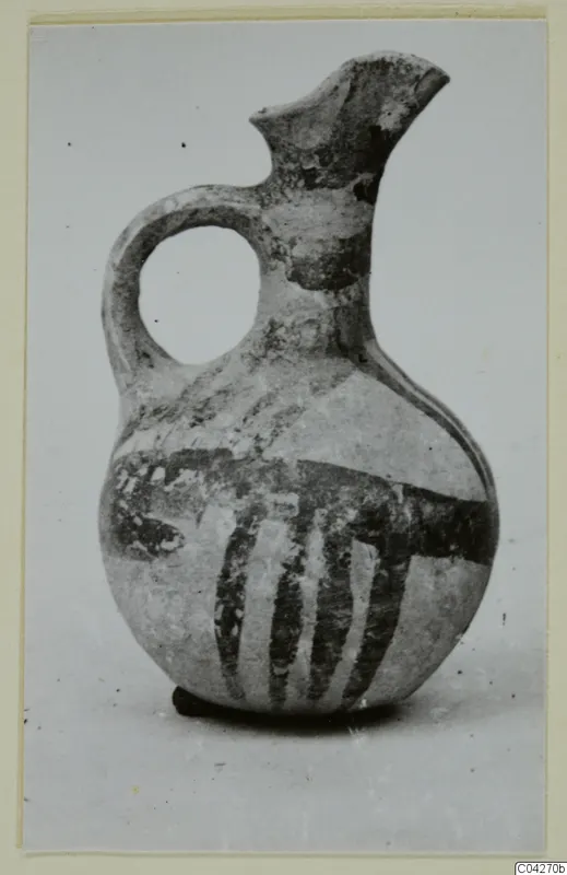 Pottery jug from Milia with a loop handle and dark painted bands on a pale surface
