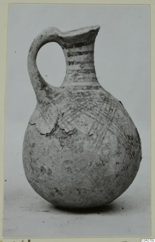 Pottery juglet with a looped handle and painted bands and crosshatching on a rounded body