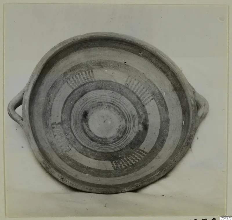 Shallow two-handled bowl with concentric painted bands and combed motifs, photographed from above.