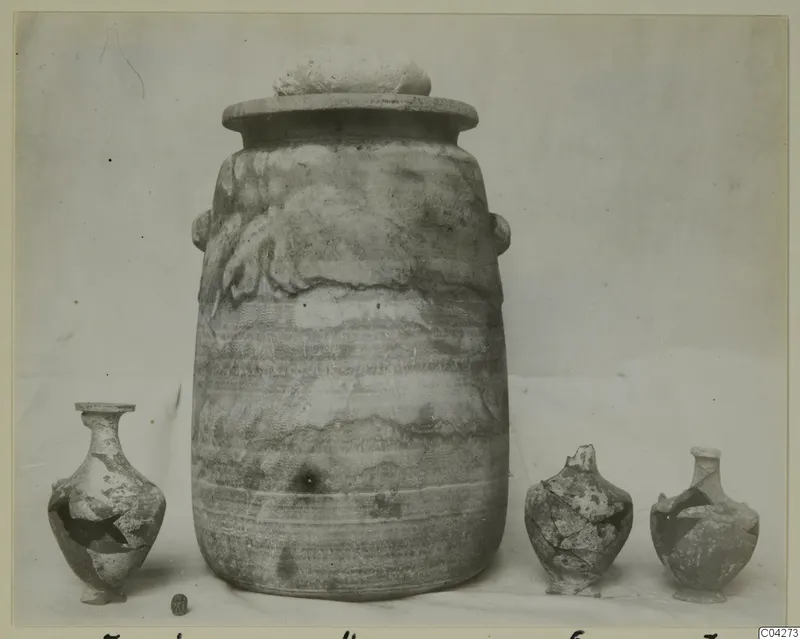 Alabaster vases from Amathus: one large lidded stone jar with two small handles, flanked by three smaller broken vessels