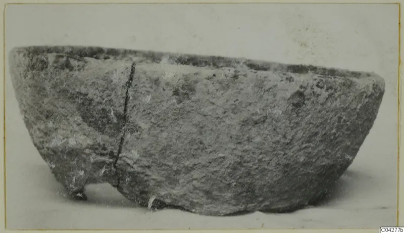Rough grey bowl with a deep crack down one side, shown in side view on a plain background