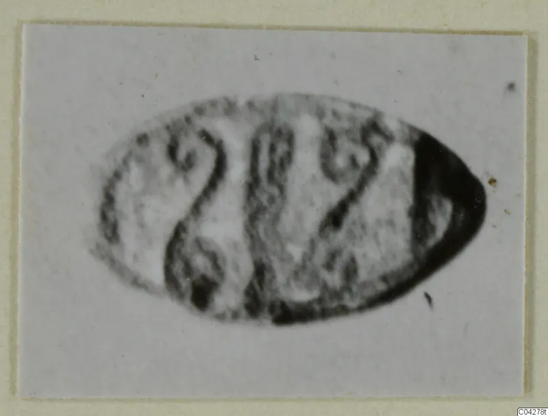 Oval glyptic object from Amathus with engraved markings, shown in a blurred close view.