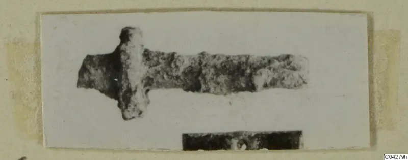 Corroded metal object from Amathus with a long bar and a short crosspiece near one end.
