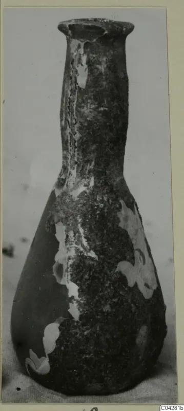 Glass bottle from Amathus with a long neck, flared rim and pear-shaped body, its surface heavily encrusted