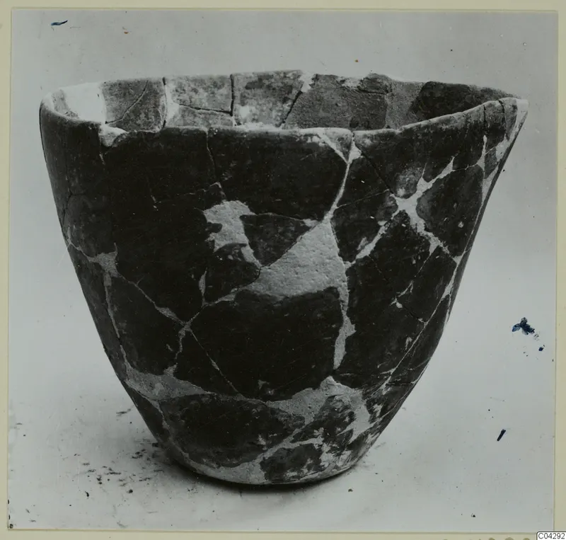 Reassembled pottery vessel with pale filler in the joins between sherds, seen from the side.