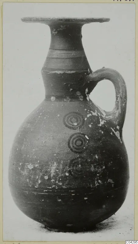 Bichrome-Red pottery jug with a flared rim, one loop handle and concentric circles painted on the body