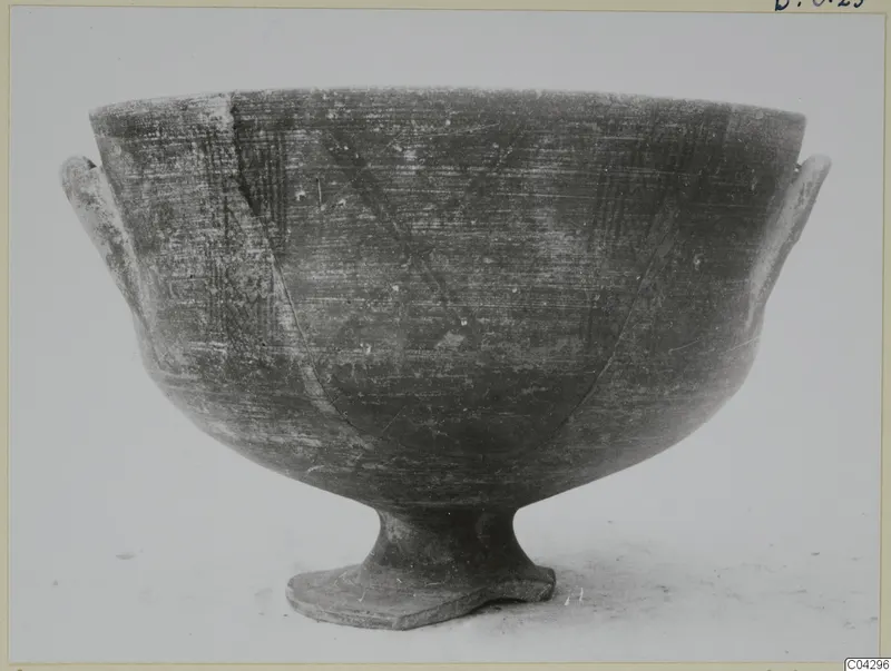 Footed bowl with two small side handles and scratched hatched decoration, shown on a pale surface