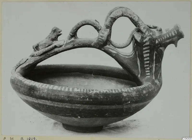Pottery White Painted III-1 bowl with a high looping handle, a small animal figure on top and white painted bands