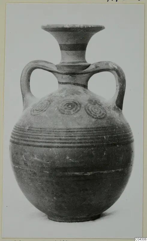 Round-bodied jug with flaring neck, two loop handles, dark painted bands and concentric circles, photographed against a plain background.