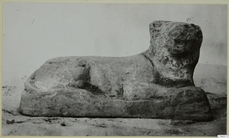 Small recumbent animal figure with a broad head and a rectangular base, seen from the side