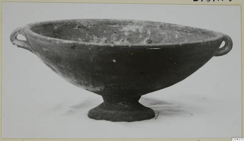 Pottery bowl with two loop handles and a short foot, photographed against a pale background