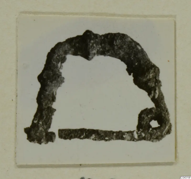 Corroded bronze object shaped like an arch, with a small loop at its right end, from Amathus