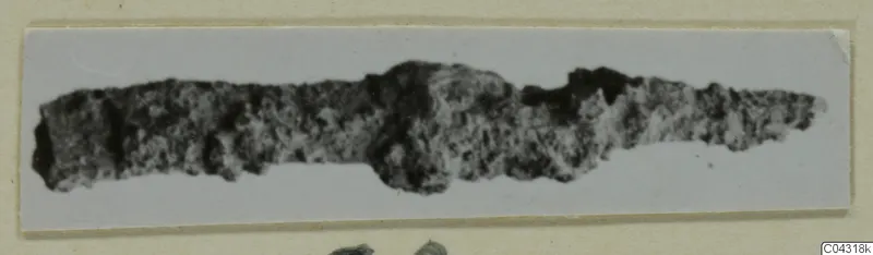 Corroded metal object from Amathus, elongated with a broader bulge near the middle, shown on a card mount.