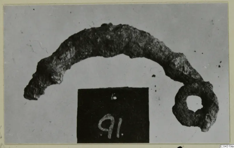 Corroded bronze object, curved like an arc with a ring at one end, from Amathus