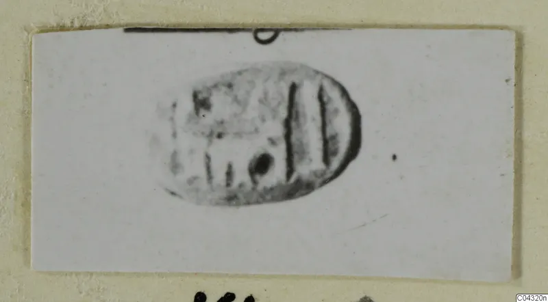 Engraved oval seal or gem with vertical incised lines and a round dot, photographed on a card mount