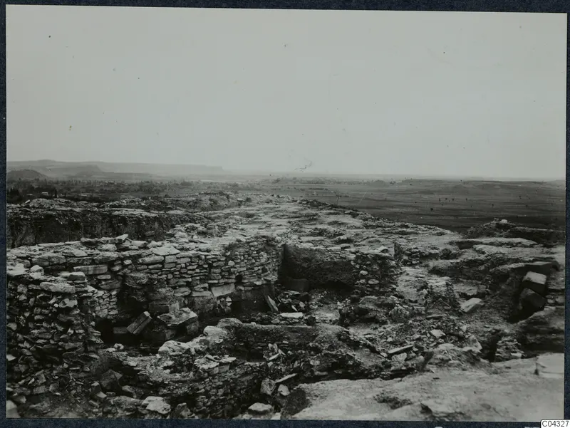 Idalion acropolis, stone walls and scattered rubble during excavation, with a open plain and hills beyond