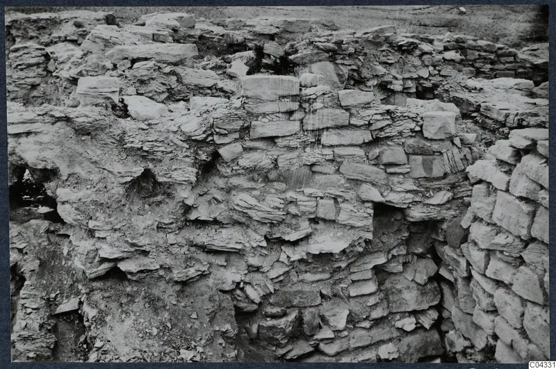 Excavated stone walls at the Idalion acropolis, with rough courses of stone and soil around them.