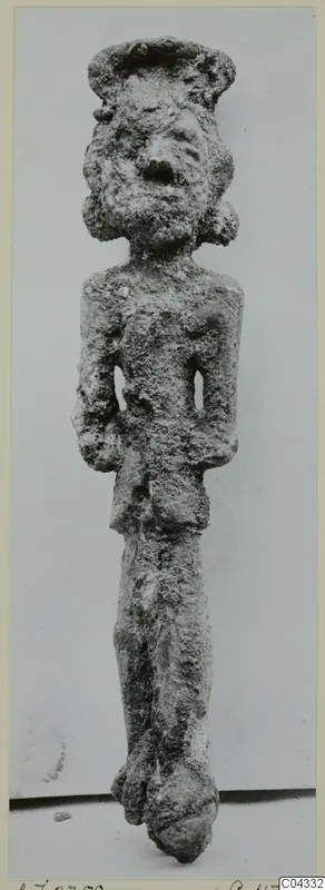 Corroded bronze figurine of a standing human figure with a wide cap or headdress