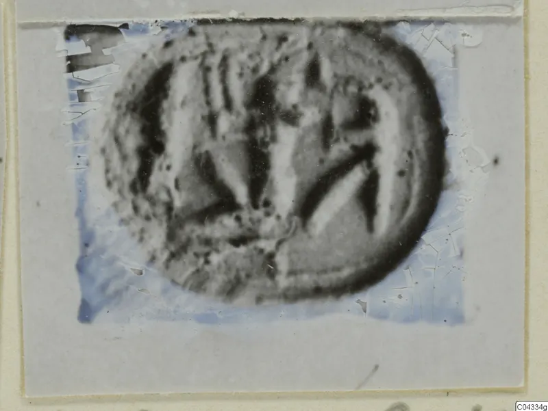 Glyptic: a rounded seal or gem with incised lines, shown in a damaged photograph on a grey card mount