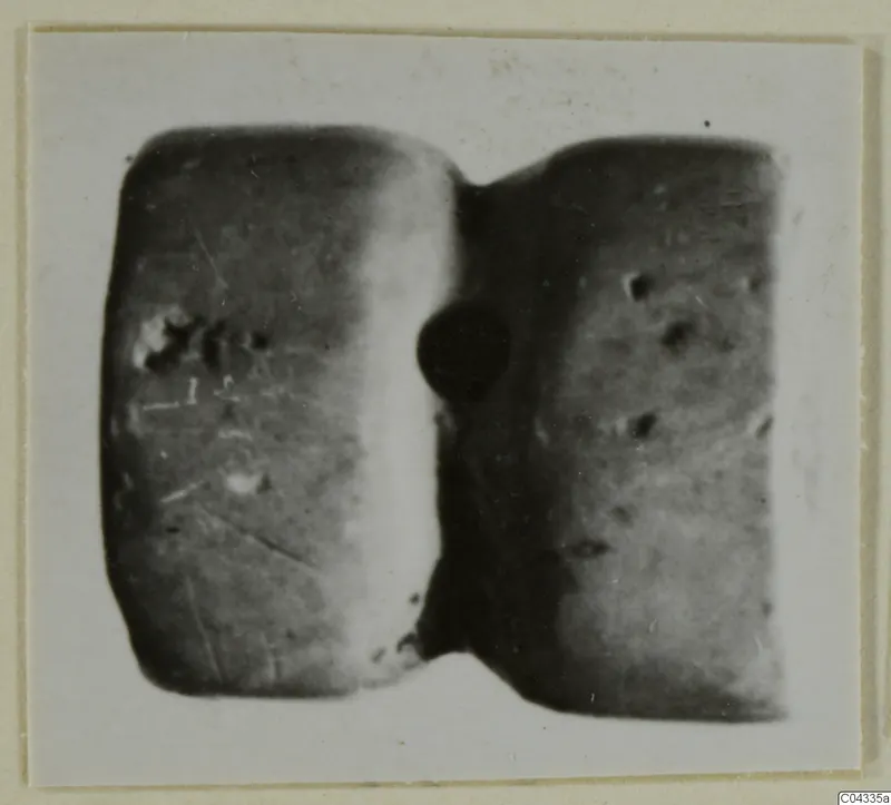 Glyptic object from Ayia Irini: a small piece with two rounded faces joined by a narrow waist, photographed close up