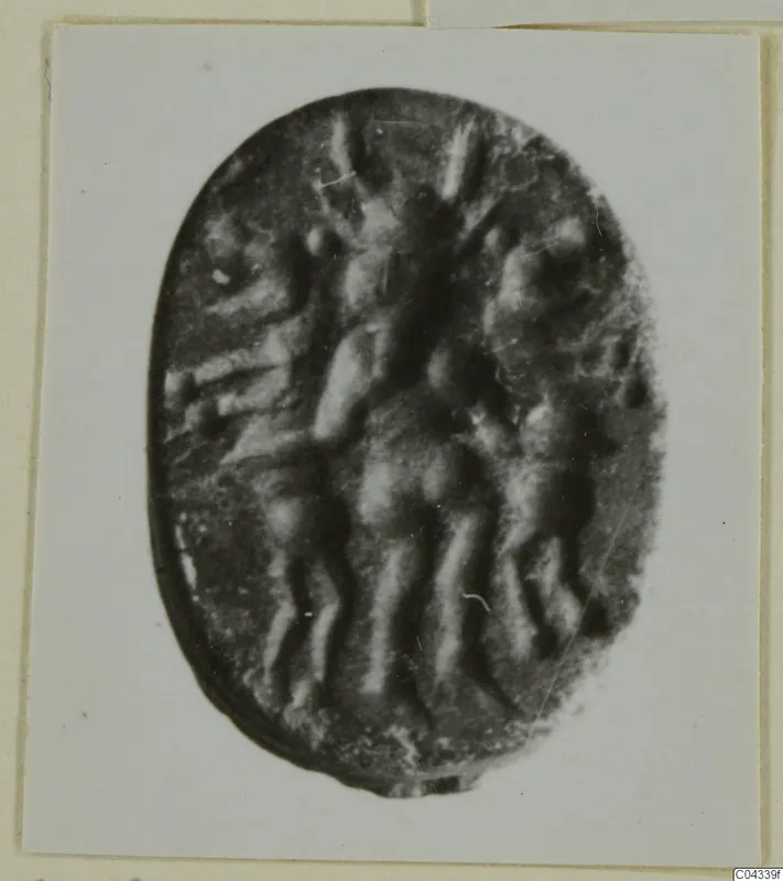 Oval dark stone seal or gem with a carved design, shown on a white card