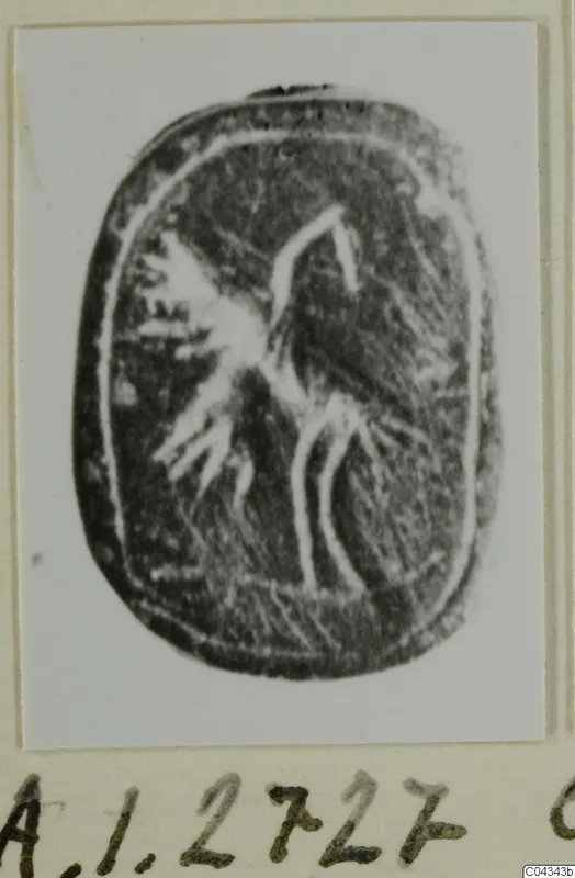 Engraved dark oval seal from Ayia Irini with a bird-like figure, photographed on a card mount