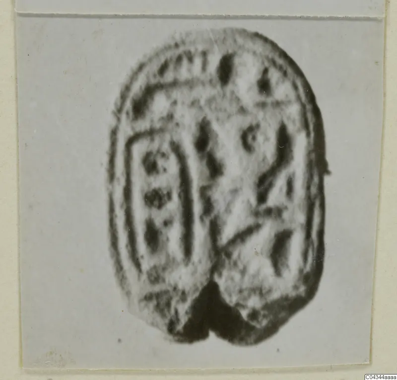 Oval stone seal with incised signs on its flat face, shown on a pale card mount