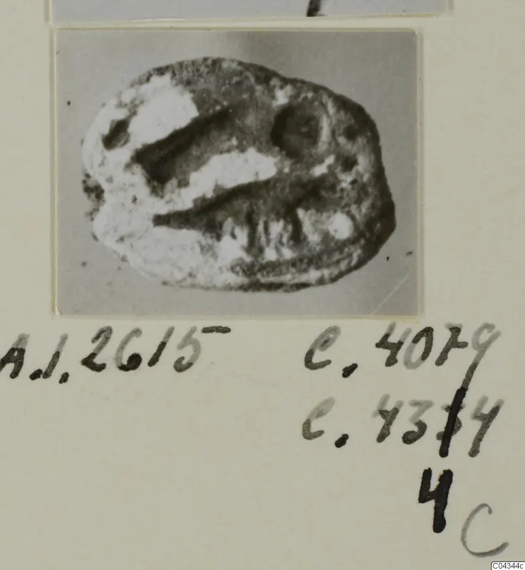 Oval seal or gem from Ayia Irini, dark and worn, with pale encrusted patches and two incised grooves