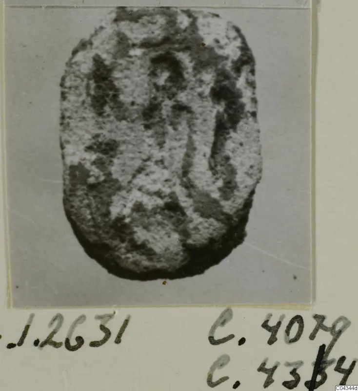 Stone seal or gem with a flat, oval face and worn engraved design, shown on a grey backdrop.