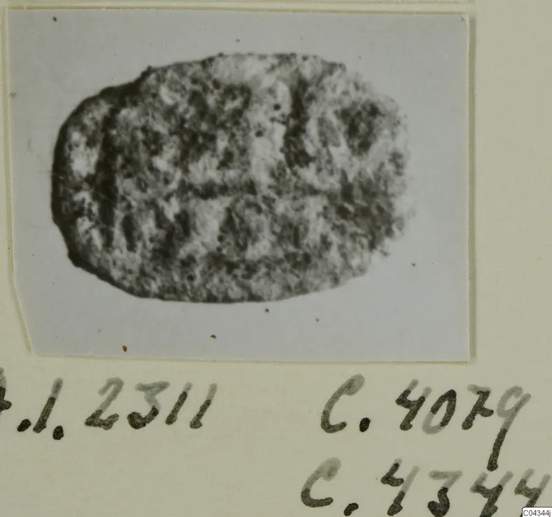 Oval glyptic object, a seal or gem with a worn engraved surface, shown on a photo card