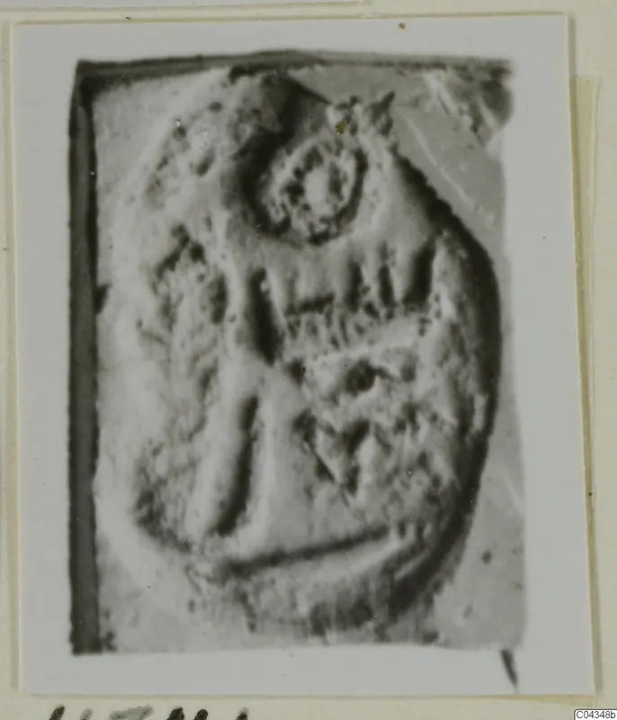 Close view of an engraved stone seal or gem with a ring-shaped motif and vertical strokes, shown on a mounted card